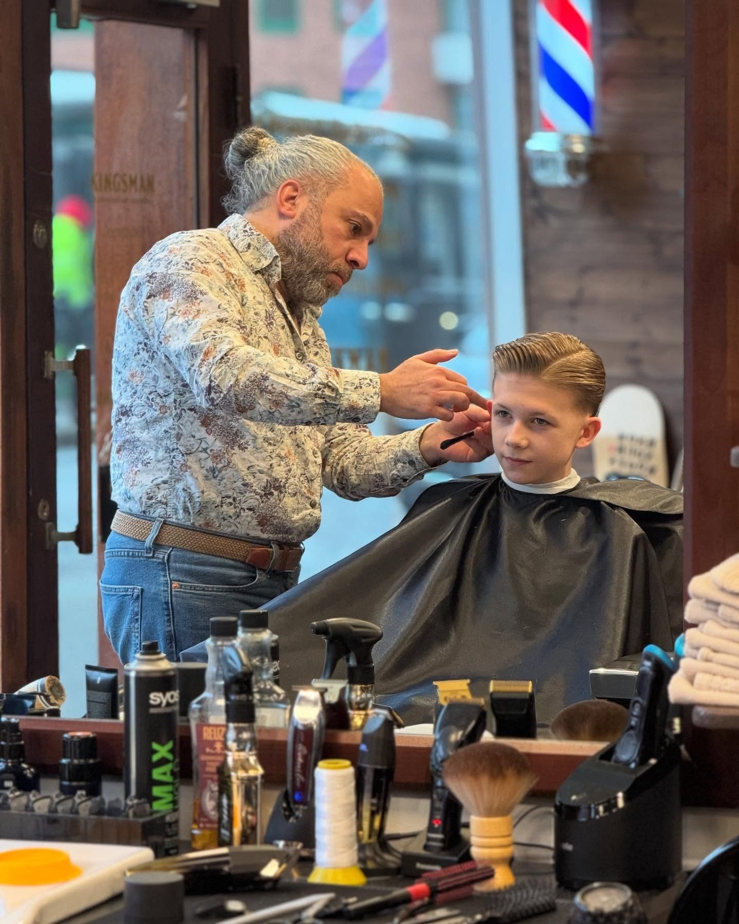 Barberare på Kingsman klipper ett barn framför det förgyllda skyltfönstret på Karl Johansgatan i Göteborg